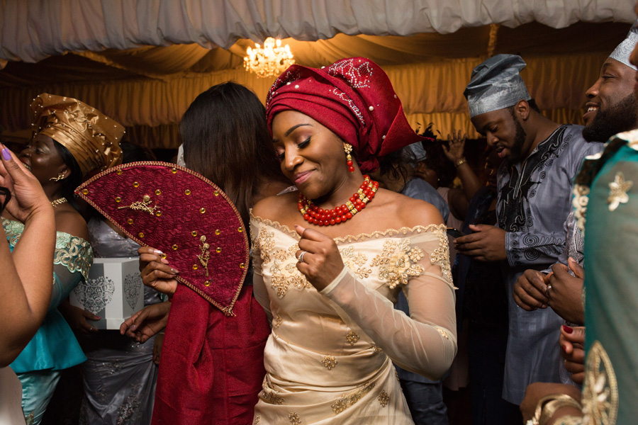 Bride dancing with a red fan during an African-British wedding reception