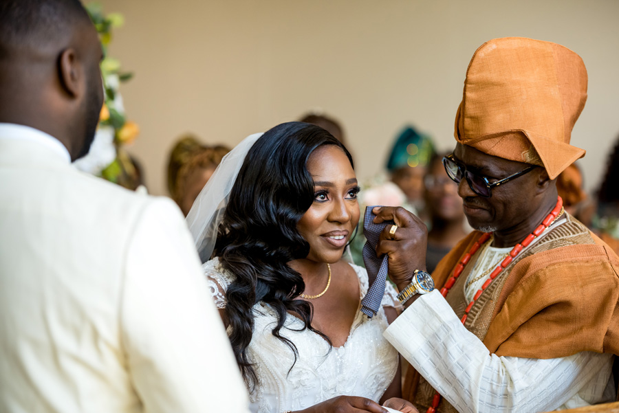 Bride during her African-British wedding ceremony as her father gently wipes her face