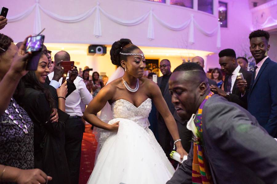Bride and groom dancing together during their African-British wedding reception surrounded by guests