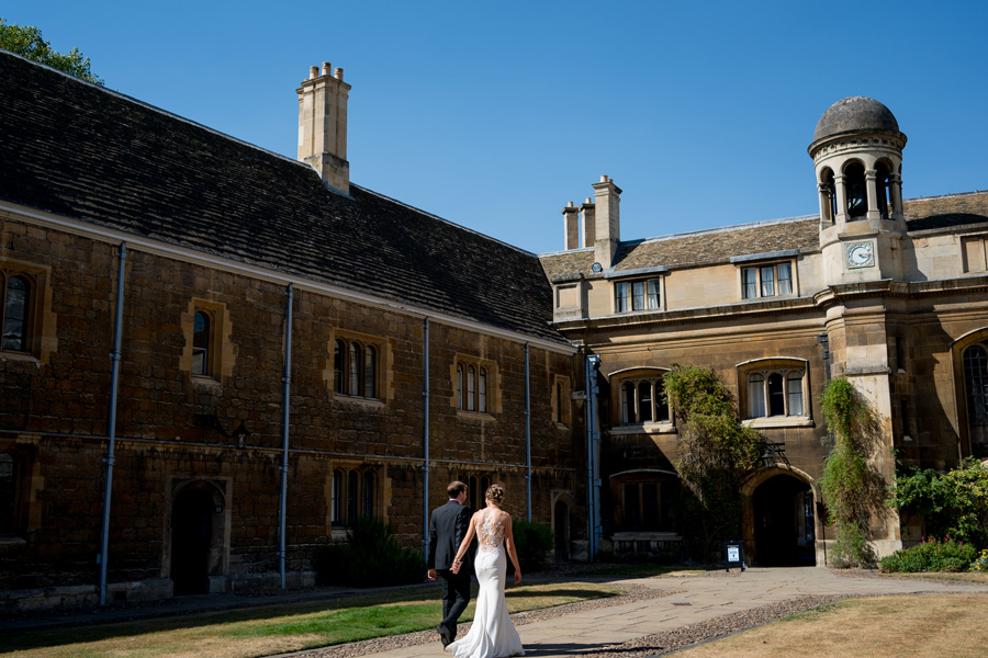 Bride and groom walking through courtyard at Gonville and Caius College Cambridge