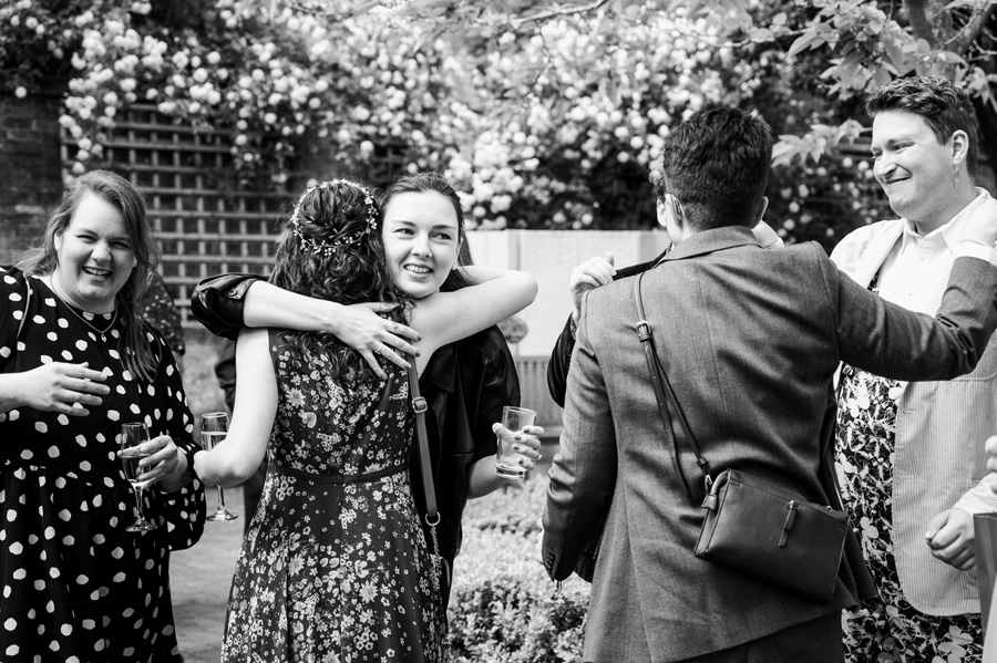 Guests embracing during a wedding drinks reception at Poets House, Ely