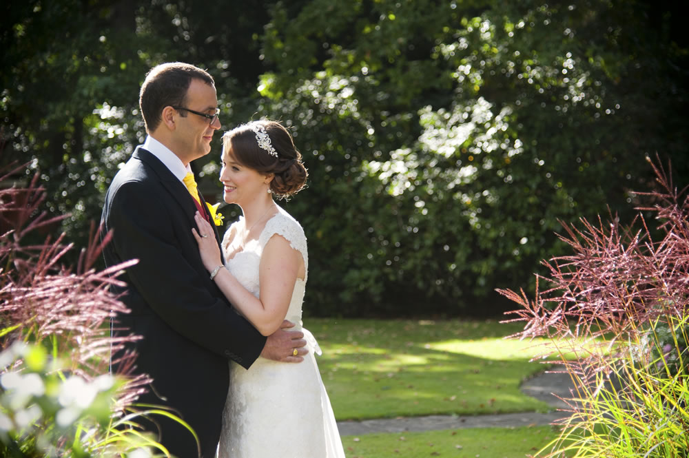 Newlyweds having a private moment in the gardens of Warren House