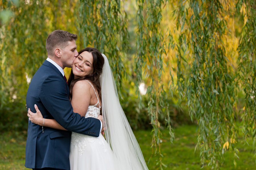 Couple hugging next to willow tree