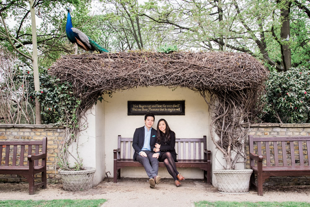 Couple sat on covered bench with a peacock on the roof