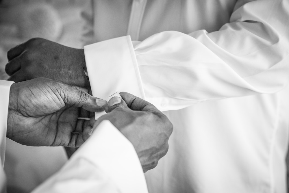 Best man helping groom with cufflinks