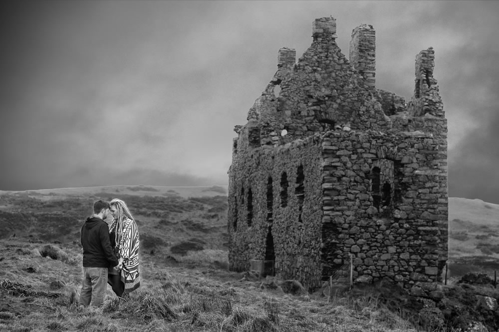 Couple with foreheads touching next to castle ruins