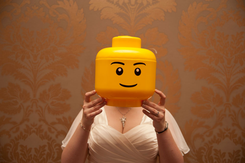 Bride holding giant lego head in front of her face