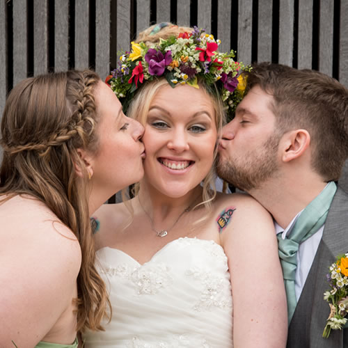 Bride kissed by groom and bridesmaid
